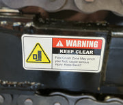 WARNING KEEP CLEAR. Foot Crush Zone on Paddock Walk Behind Trencher with Guide Wheel may pinch your foot, causing serious injury. Keep Back! Yellow symbol shows a foot being pinched. For use with Paddock portable trencher models.