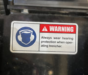Warning sign with ear protection icon and text: WARNING: Always wear hearing protection when operating the Paddock Walk Behind Trencher with Guide Wheel by Paddock.