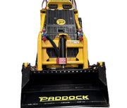 Front view of a Paddock Tracked Mini Loader Pro by Scintex in yellow, featuring a black scoop, hydraulic components, and grille. Powered by a diesel engine, its ideal for heavy-duty construction or landscaping tasks favored by top companies.