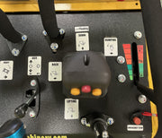 Close-up of the Paddock Tracked Mini Loader Pro control panel, showing labeled levers and buttons for lifting, dumping, and emergency stop. The main joystick features yellow and red buttons with clear directional labels. Powered by a 40hp Perkins turbo diesel engine.