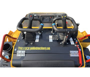 Close-up of the controls on a PADDOCK™ Tracked Mini Loader Elite, featuring twin levers, a display screen, multiple buttons, and safety labels—hallmark elements of advanced construction machines powered by a 58hp Yanmar 4-cylinder Turbo Diesel engine. Both the PADDOCK brand and paddockmachinery.com are visible against a white background.
