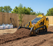 A Paddock Tracked Mini Loader (35hp Kubota Diesel Engine) with free 4in1 bucket spreads soil in a backyard near a wooden fence, shovels and large white material bags visible in the sunny background.