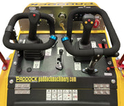 Close-up of the Paddock Tracked Mini Loader Pro - Diesel Engine control panel, showing two joysticks, labeled switches, warning stickers, and Paddock branding on a yellow-black surface—perfect for construction professionals.