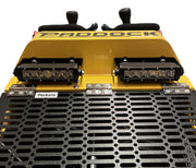 Close-up of the front of a yellow Paddock Tracked Mini Loader Pro - Diesel Engine by Paddock, showing a black metal grille, twin LED light bars, Perkins branding, plus visible levers and seats at the top.